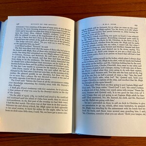 K&ouml;nnte beinhalten: Eine Nahaufnahme eines ge&ouml;ffneten Buches mit einer vergilbten Seite, die Text aus dem Buch "Mutiny on the Bounty" von Kapit&auml;n Bligh zeigt. Der Text beschreibt die Ereignisse, die zur Meuterei auf der Bounty f&uuml;hrten.