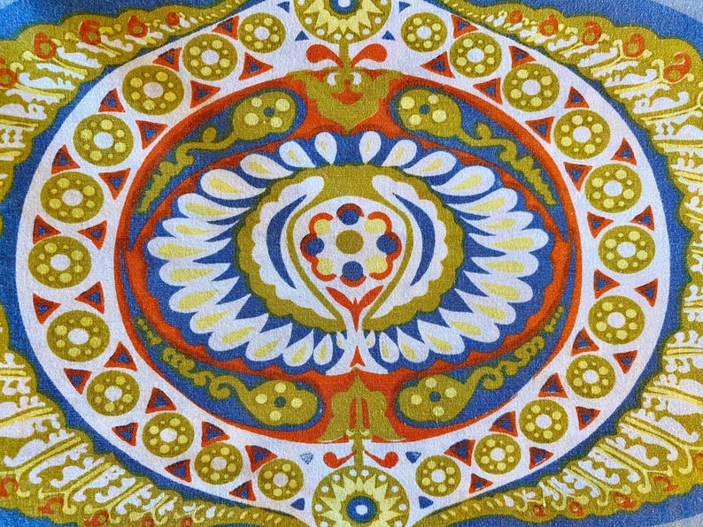 May include: A colorful, circular pattern with a blue, orange, and yellow color scheme. The pattern features a central design with a flower-like shape and repeating geometric shapes around the edges.