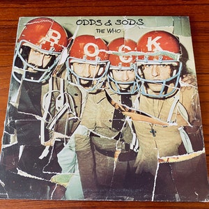 May include: A vintage vinyl record album cover featuring The Who. The cover art is a collage of the band members wearing football helmets with the words "Odds & Sods" and "The Who" printed on the cover.