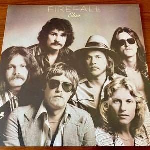 May include: A vintage vinyl record album cover featuring a band called "Elan" with the album title "Firefall". The cover features a group of six men with long hair, wearing casual clothing, and looking directly at the camera.