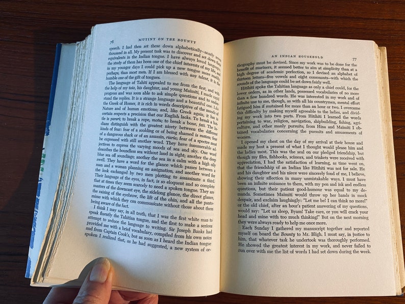K&ouml;nnte beinhalten: Ein offenes Buch mit zwei sichtbaren Seiten. Die linke Seite tr&auml;gt den Titel "Mutiny on the Bounty" und die rechte Seite den Titel "An Indian Household". Beide Seiten haben Text in schwarzer Tinte.