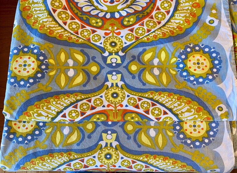May include: A blue and yellow patterned fabric with a paisley design. The fabric features a repeating pattern of circles, leaves, and swirls.