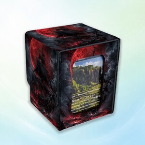 May include: A rectangular trading card deck box featuring a dark fantasy illustration of a red moon and a black ship on a stormy sea. The front panel has a clear window displaying a game card with a landscape image and text including Mountain Plains Swamp.
