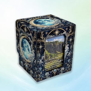 May include: A square deck box featuring a dark blue celestial design with gold filigree, stars, and a full moon. The front panel has a cutout window displaying a trading card with a landscape illustration and text including Mountain, Plains, Swamp.