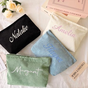 May include: Four rectangular corduroy pouches in black, cream, light blue, and sage green. Each pouch features embroidered names: Natalie in white, Amelia in pink, Harper in blue, and Margaret in white, written in a cursive script font.