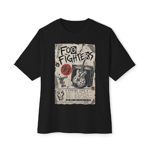 May include: A black t-shirt featuring a graphic print of a 1996 Foo Fighters concert tour poster. The design includes the band name, a guitar, an amplifier, a skull icon, and a list of tour dates and locations in a distressed, vintage-style layout.