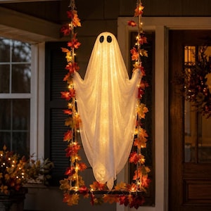 Peut inclure: Une décoration de fantôme blanc lumineux suspendue à une balançoire, éclairée par des lumières internes. Les cordes de la balançoire sont ornées de feuilles d'automne artificielles aux tons rouge, orange et jaune pour une décoration festive.