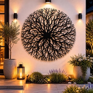 May include: A large, circular black metal wall art piece featuring an intricate, branching root or coral-like design. The artwork is mounted on a light-colored exterior wall, positioned symmetrically between two wall-mounted outdoor light fixtures.