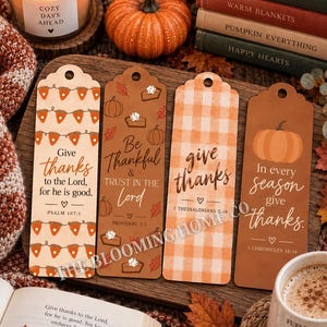May include: Four rectangular bookmarks with rounded tops and holes, featuring autumn-themed designs. They display religious text including Psalm 107:1, Proverbs 3:5, 1 Thessalonians 5:18, and 1 Chronicles 16:34, decorated with pumpkins, pie slices, and plaid patterns.
