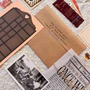 May include: A collection of vintage ephemera including a brown kraft envelope addressed to The Trinket Post, a black and white photograph of people, a printed paper bundle tied with twine, a wooden shelf illustration, and various stamps and bookmarks.