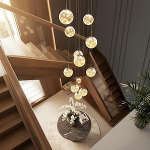 May include: A multi-light pendant chandelier featuring numerous spherical glass globes suspended at varying heights. Each clear glass sphere contains warm, glowing internal lights, creating a cluster of illuminated orbs that hang vertically above a round table.