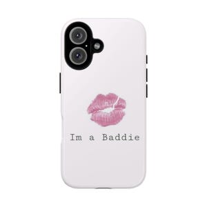 Könnte beinhalten: Eine weiße Smartphone-Hülle mit einem pinkfarbenen Lippenstift-Kussabdruck über dem schwarzen Schriftzug Im a Baddie. Die Hülle hat oben links eine schwarze Kameraaussparung mit zwei kreisförmigen Linsen und einem kleinen Blitzlicht.