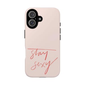 Könnte beinhalten: Eine blassrosa Smartphone-Hülle mit einem schwarzen Kameramodul oben links und dem Text stay sexy in korallfarbener Schreibschrift mit einer horizontalen Linie über dem Wort stay auf der unteren Hälfte der Hülle.