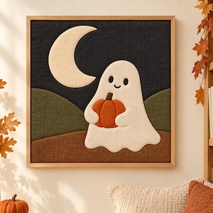 May include: A square framed textile wall art piece featuring a layered fabric applique design. The scene depicts a white ghost holding an orange pumpkin against a dark navy night sky with a cream crescent moon and rolling green and brown hills.