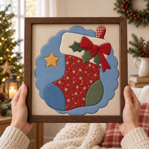 Puede incluir: Un cuadro cuadrado con una aplicación de tela en forma de calcetín navideño. El calcetín tiene un estampado floral rojo, una punta azul y un puño crema con un lazo rojo, hojas de acebo verdes y un bastón de caramelo a cuadros rojos y blancos.
