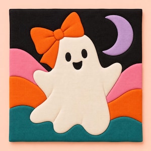 May include: A square fabric wall hanging featuring a white ghost with an orange bow on its head. The background displays a black sky with a lavender crescent moon and layered, wavy hills in shades of pink, orange, and teal green.