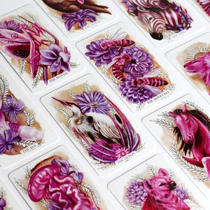 Pink and purple tarot and oracle cards featuring animals, flowers, plants and crystals.