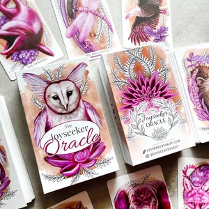 May include: A set of oracle cards with a purple and white color scheme. The cards feature illustrations of animals and nature. The box for the cards has the title "The Joyseeker Oracle" and the website address "joyseekertarot.com".