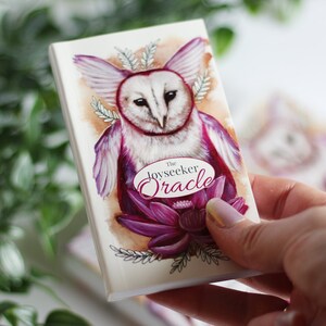 Pink and purple tarot and oracle cards featuring animals, flowers, plants and crystals.