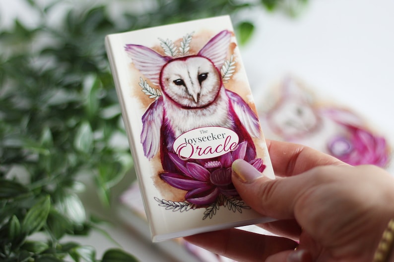 Pink and purple tarot and oracle cards featuring animals, flowers, plants and crystals.