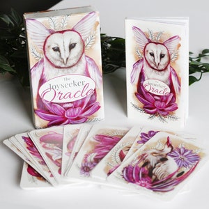 Pink and purple tarot and oracle cards featuring animals, flowers, plants and crystals.