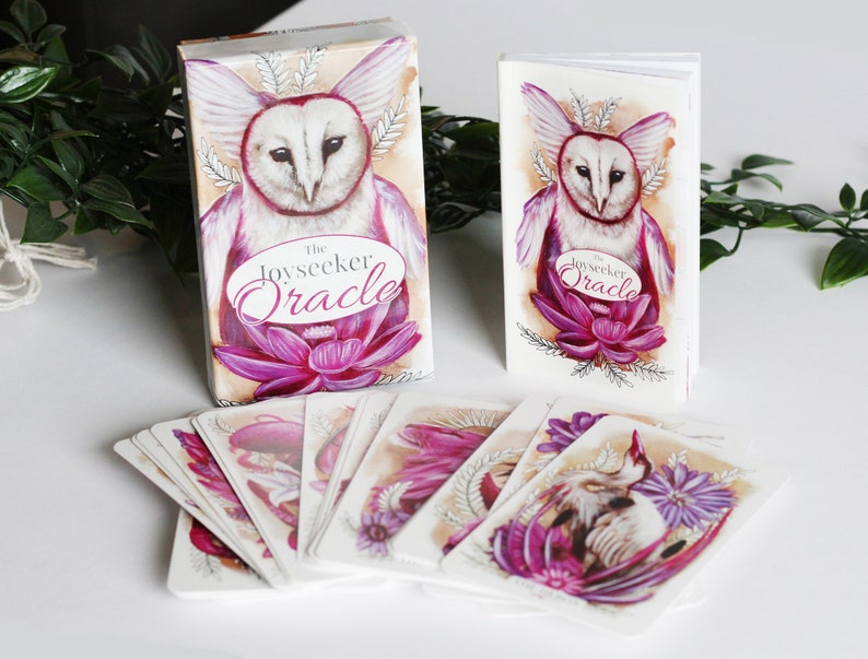 Pink and purple tarot and oracle cards featuring animals, flowers, plants and crystals.
