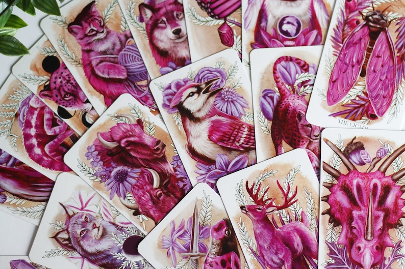 Pink and purple tarot and oracle cards featuring animals, flowers, plants and crystals.