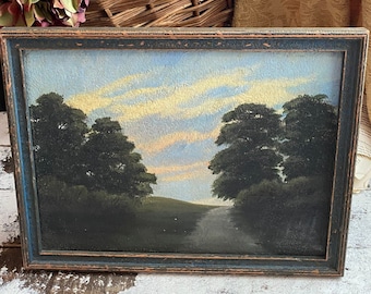 May include: A framed painting of a landscape scene with two dark green trees on either side of a path leading to a hill. The sky is a light blue with yellow clouds. The frame is dark blue with a gold trim.