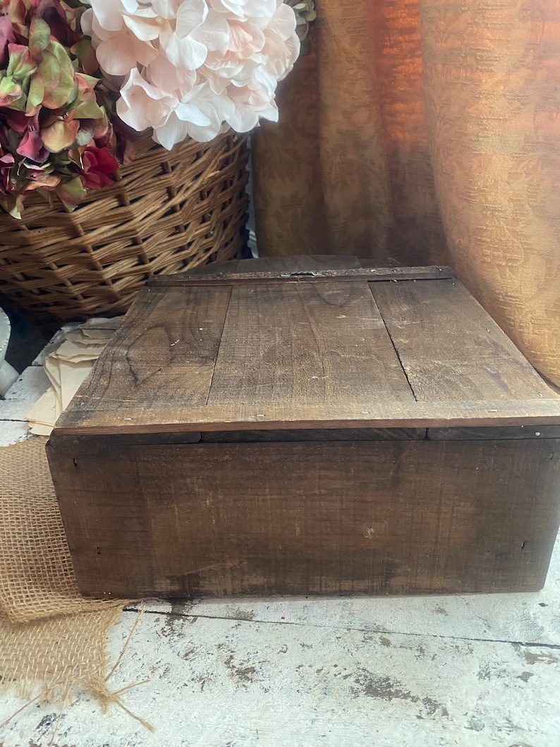Pu&ograve; includere: Una scatola di legno con un coperchio incernierato e una chiusura in metallo. La scatola &egrave; in legno marrone scuro e ha un aspetto rustico.