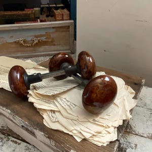 May include: Four brown ceramic door knobs with a metallic finish. The knobs are arranged on a stack of old, white paper.