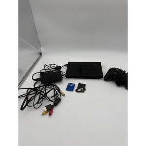 May include: A black video game console with a power adapter, a wired controller, a blue memory card, a black memory card with a white logo, and a multi-colored AV cable with yellow, white, and red connectors for audio and video output.