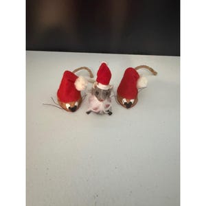 May include: Three small decorative figures consisting of two brown walnut shell mice with red felt Santa hats and white pom-poms, and one central grey fuzzy mouse figure wearing a red felt Santa hat with a white trim and a white beard.