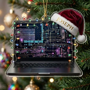 May include: A flat, clear acrylic Christmas ornament shaped like a laptop computer. The screen displays a dark blue circuit board pattern. A string of colorful Christmas lights frames the screen, and a red Santa hat with the name JOSEPH is attached.