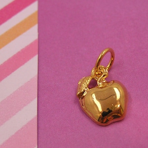 Puede incluir: Un charm de manzana de color dorado con un bucle para sujetarlo a un collar o pulsera.