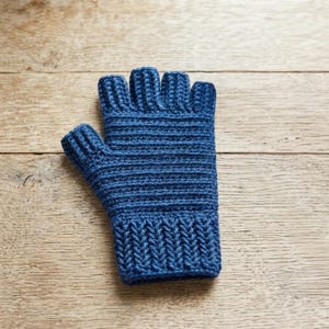 May include: A blue fingerless glove featuring a ribbed cuff at the wrist and a textured, horizontally stitched pattern across the hand and fingers. The design leaves the fingers exposed, providing a clear view of the crochet construction.