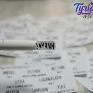 May include: A white marker pen with a black label that says "SAMHAIN" on it. The marker is held over a stack of white cards with black text on them.