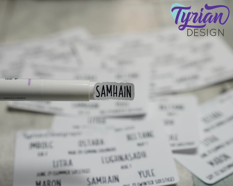 May include: A white marker pen with a black label that says "SAMHAIN" on it. The marker is held over a stack of white cards with black text on them.