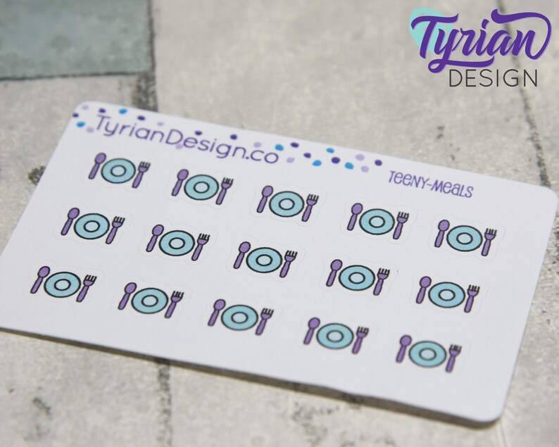 May include: A sheet of 15 stickers featuring a blue plate, purple fork and spoon. The text "TEENY-MEALS" is printed on the sheet.
