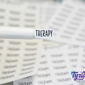 May include: A white marker pen with the word "THERAPY" printed on a white sticker attached to the end of the pen.