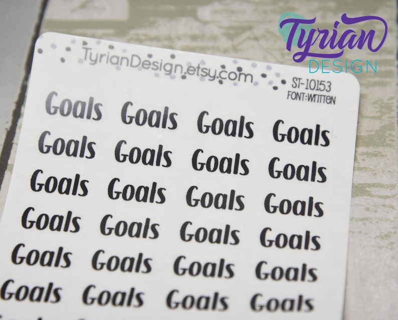 May include: White sticker sheet with the word "Goals" printed in a black, handwritten font. The sticker sheet has the text "TyrianDesign.etsy.com" and "ST-10153 FONT:WITTEN" printed on it. The stickers are arranged in rows.