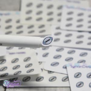May include: A sheet of white stickers with a football design. The football is outlined in black and filled with a light purple and blue pattern. The stickers are arranged in rows and columns.