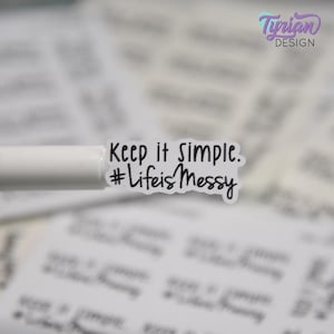 May include: A small white rectangular sticker with rounded corners featuring the black printed text Keep it simple. #LifeisMessy. The sticker is held by a white tool, with multiple identical stickers visible in the blurred background.