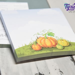 Könnte beinhalten: Ein Set Herbst-Notizblöcke mit einem hellblauen Hintergrund mit weißen Wolken und drei orangefarbenen und gelben Kürbissen auf einem Bett aus grünem Gras. Der Text "Tyrian DESIGN" befindet sich in lila in der oberen rechten Ecke des Bildes.