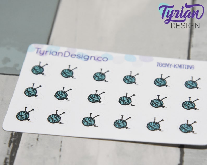 K&ouml;nnte beinhalten: Eine Blatt mit Aufklebern von tealblauen und schwarzen Wollkn&auml;ueln mit dem Text "TEENY-KNITTING" und "TyrianDesign.co" auf dem Blatt.