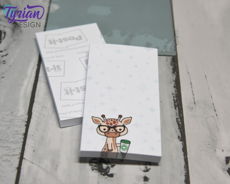 May include: A notepad with a white background and a light blue pattern of stars. The notepad has a cartoon giraffe with glasses and a cup of coffee on the front. The notepad is labeled "Post-it Note" and "Post-it" on the side.