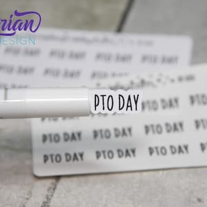 May include: A close-up of a white marker pen with a black label that reads "PTO DAY". The label is on a sheet of white paper with multiple labels that read "PTO DAY".