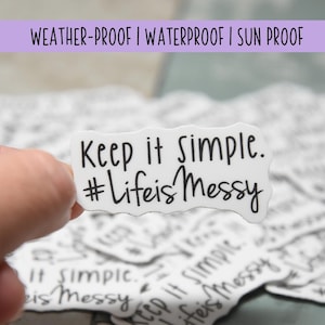 Może przedstawiać: Biała naklejka wycięta po obrysie z falistym brzegiem, zawierająca czarny nadruk z tekstem Keep it simple. #LifeisMessy. Naklejka ma gładkie wykończenie i jest częścią większej kolekcji identycznych naklejek ułożonych w stos.