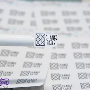 Pode incluir: Uma folha de adesivos brancos com um padrão de grade preta e o texto "CHANGE FILTER" impresso em cada adesivo. Os adesivos são projetados para serem usados como lembretes para trocar os filtros de ar.
