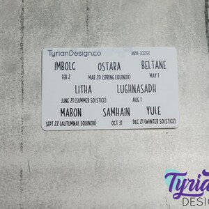 May include: White card with the text "TyrianDesign.co" and a list of eight holidays with their dates and names, including Imbolc, Ostara, Beltane, Litha, Lughnasadh, Mabon, Samhain, and Yule.