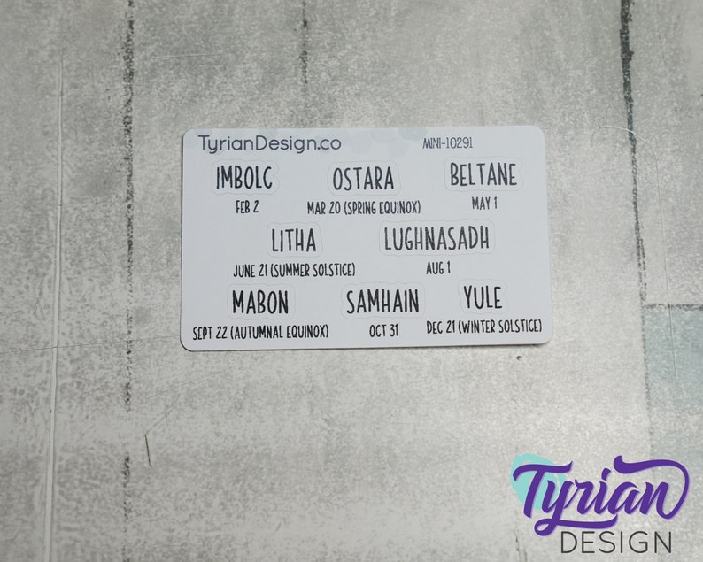 May include: White card with the text "TyrianDesign.co" and a list of eight holidays with their dates and names, including Imbolc, Ostara, Beltane, Litha, Lughnasadh, Mabon, Samhain, and Yule.